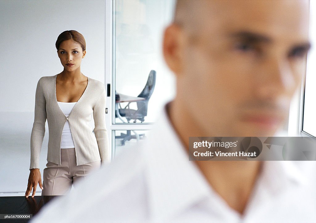 Woman looking into camera, man in blurred foreground