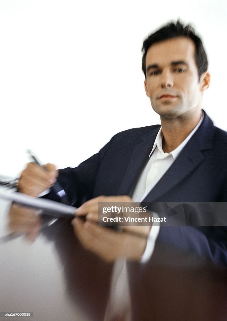 Businessman sitting at desk, blurred, portrait