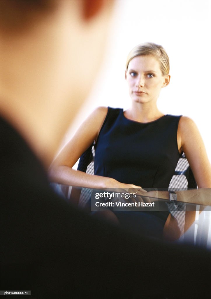 Businesswoman sitting at desk, blurred
