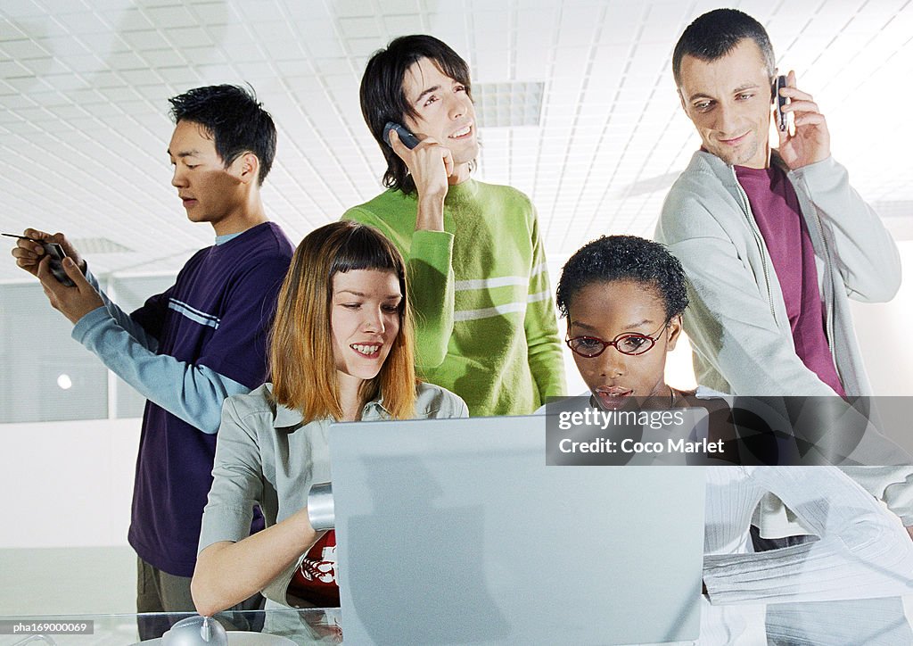 Group of people in focus, rear view of computer screen in foreground