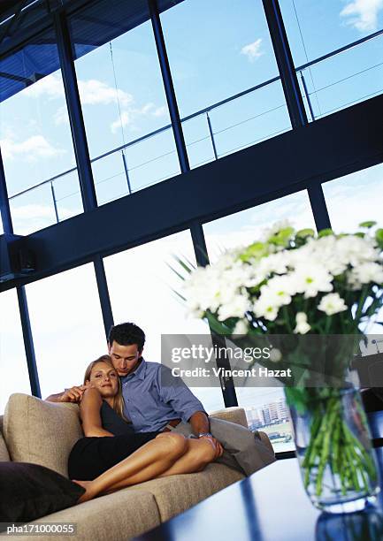 couple cuddling on sofa - bay window stock pictures, royalty-free photos & images