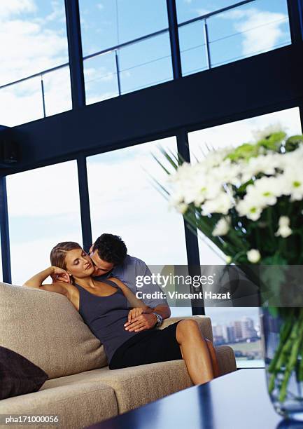 couple kissing on sofa - bay window interior stock pictures, royalty-free photos & images