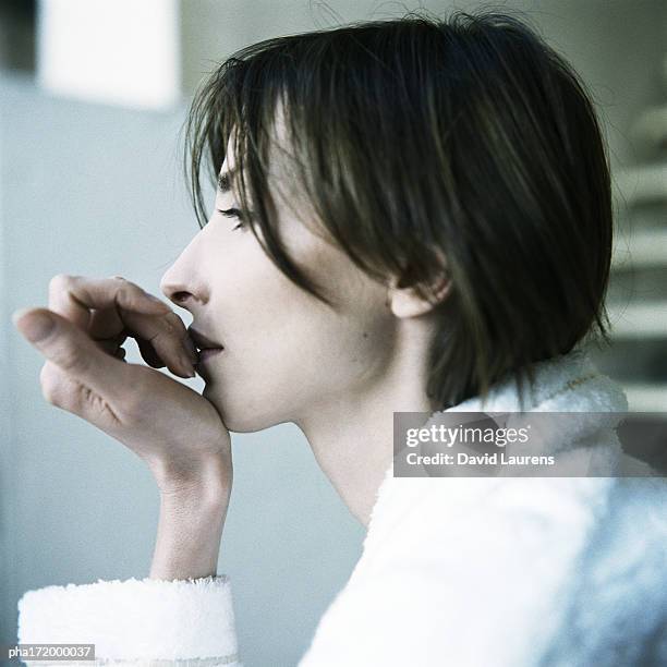 woman with hand against mouth and chin, side view - laurens foto e immagini stock