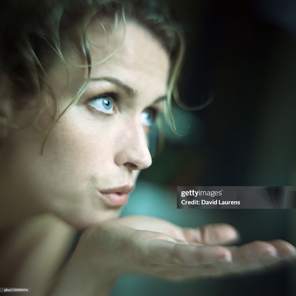 Woman blowing on palm of hand, close up