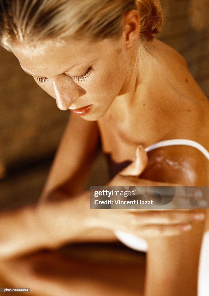 Woman putting lotion on shoulder