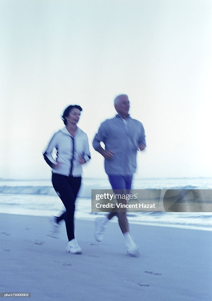 Mature man and woman running on beach