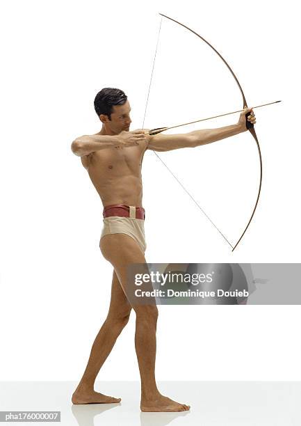 half-nude man bending bow, side view - arco y flecha fotografías e imágenes de stock