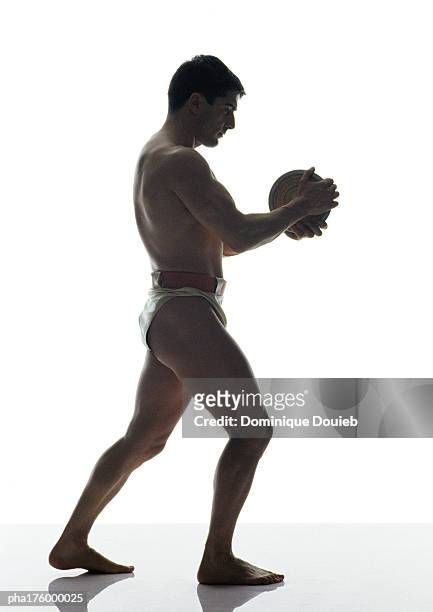 half-nude man holding discus, side view - saut et lancer d'athlétisme masculin photos et images de collection
