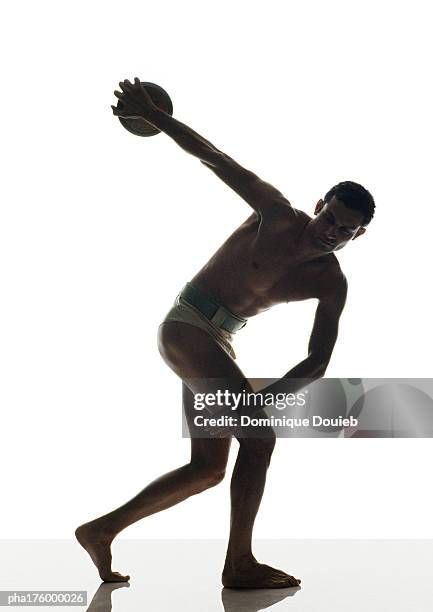 half-nude man preparing to throw discus, side view - mens field event stockfoto's en -beelden