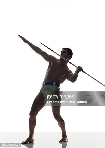 half-nude man preparing to throw javelin, side view - mens field event stockfoto's en -beelden