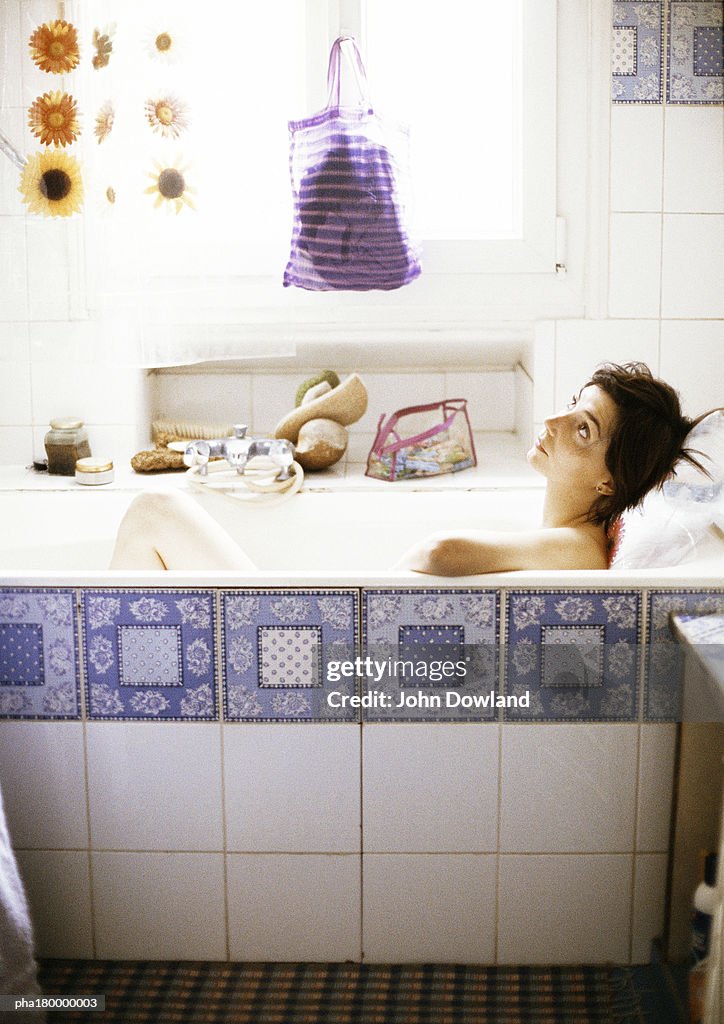 Woman in bathtub, looking up, side view