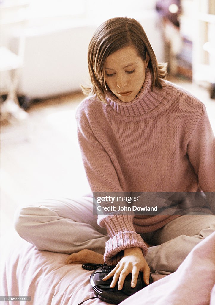 Woman sitting on bed with hand on phone