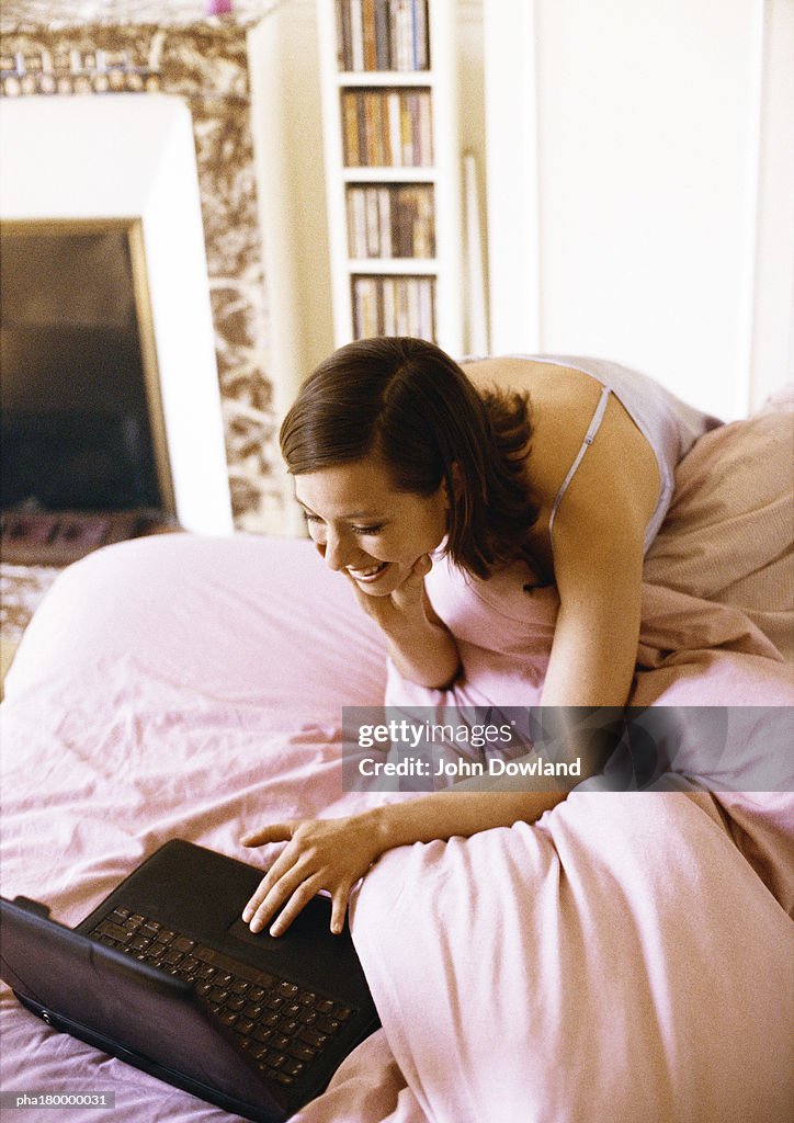 Woman using laptop computer on bed