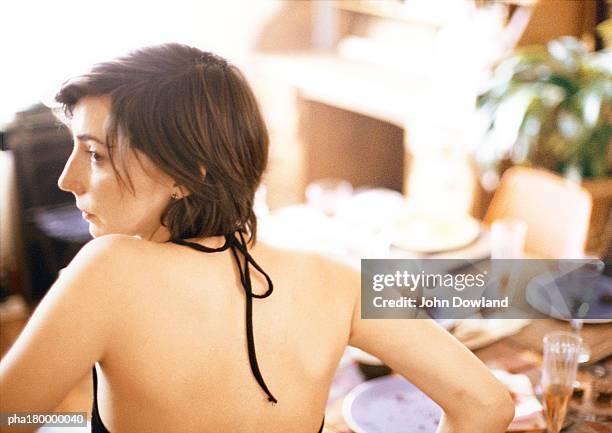 woman at table, wearing evening dress, rear view - being watched stockfoto's en -beelden