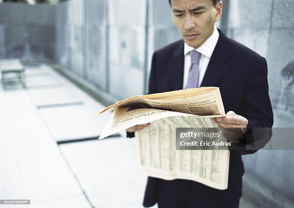 Businessman reading newspaper, waist up, long shot