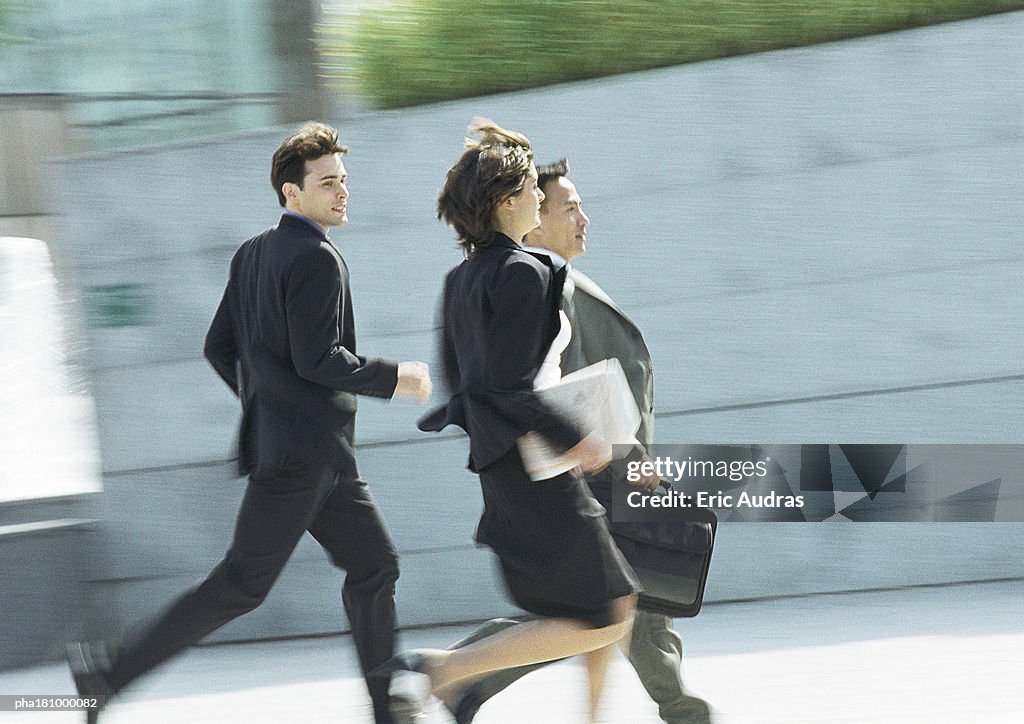 Business people running outdoors, blurred motion