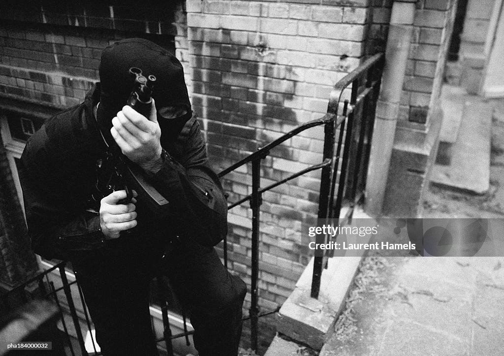 Masked man holding sub-machine gun, b&w