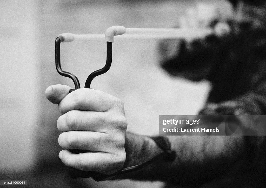 Hands holding sling shot, close-up, b&w