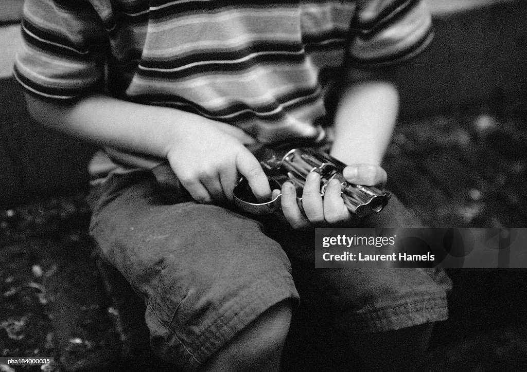 Child holding gun, mid-section, b&w