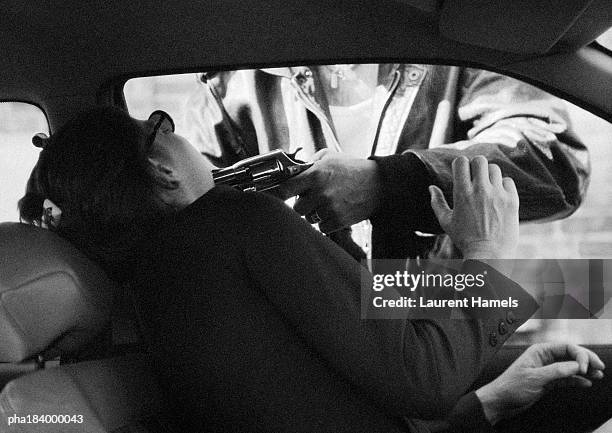 man threatening woman in car with gun, b&w - assassino - fotografias e filmes do acervo