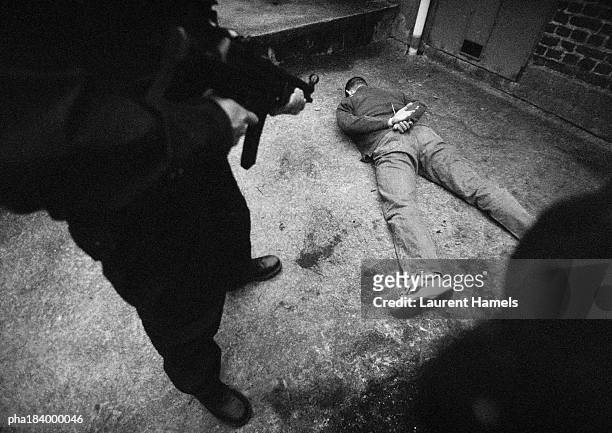 man with sub-machine gun threatening man on floor, b&w - killing stock pictures, royalty-free photos & images