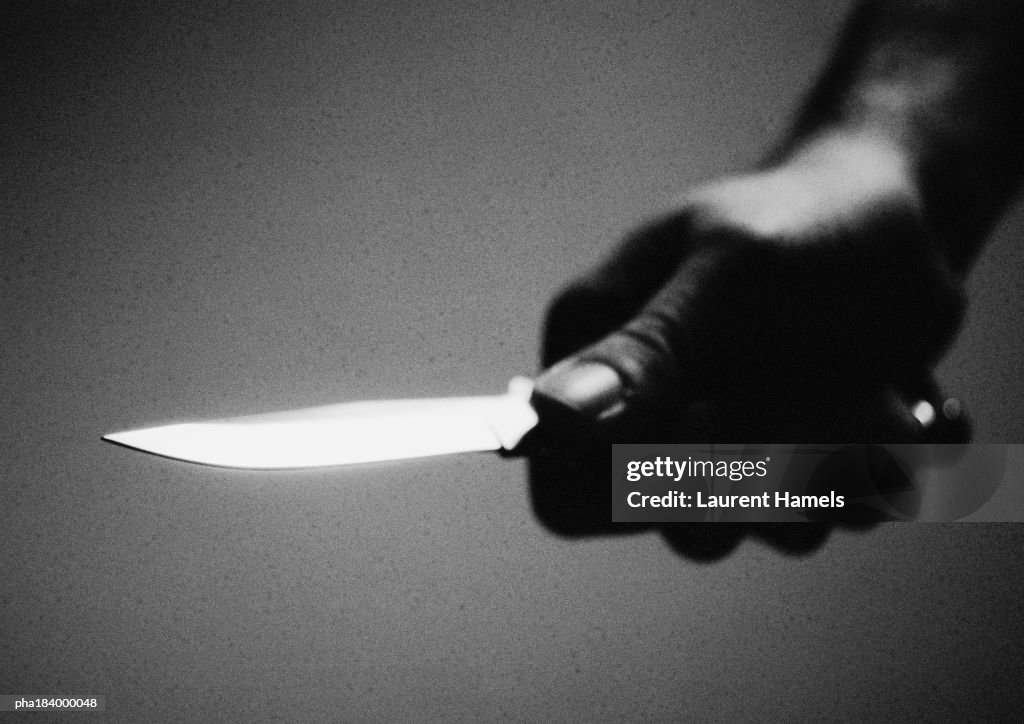Hand holding knife, close-up, b&w