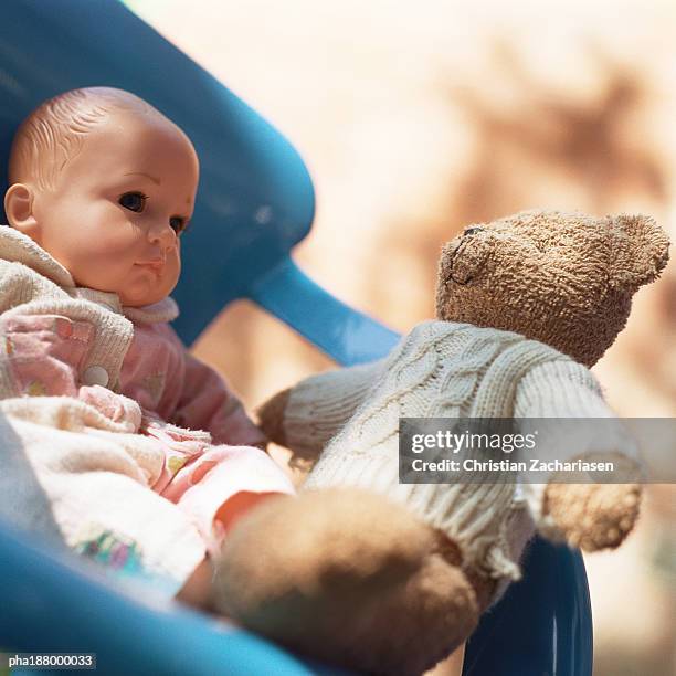 teddy bear sitting in chair with baby doll. - baby doll fotografías e imágenes de stock