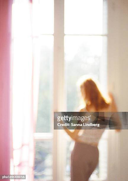 woman looking out of window, rear view, three quarter length, blurred. - three quarter length stock-fotos und bilder
