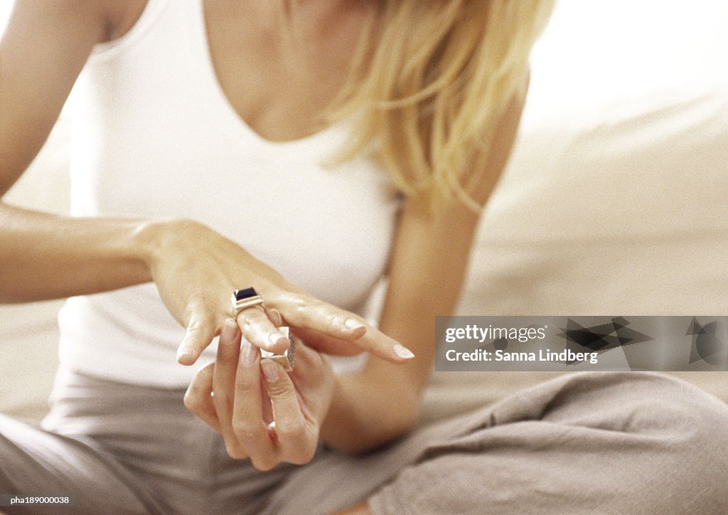 Woman putting ring on finger, mid-section, close up.