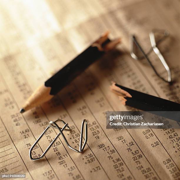 broken pencil and twisted paper clips on top of financial numbers. - share prices of consumer companies pushes dow jones industrials average sharply higher stockfoto's en -beelden