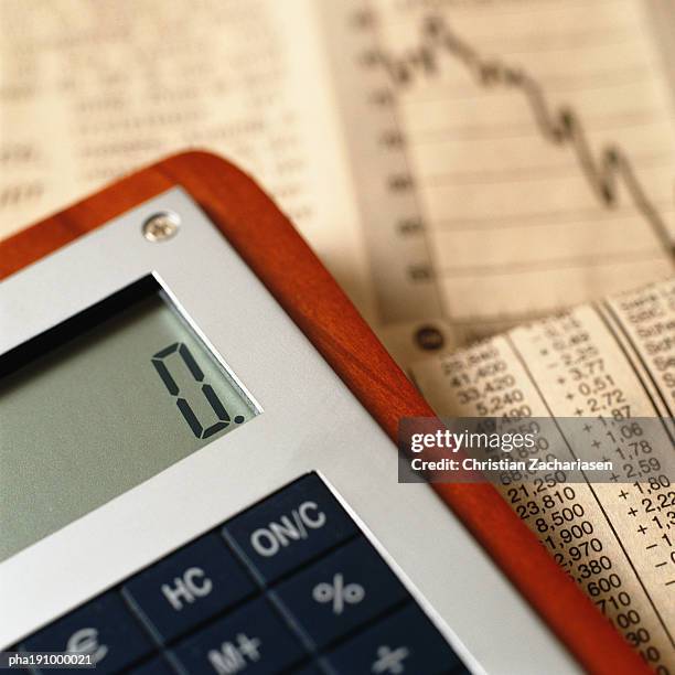 calculator on top of financial charts. - share prices of consumer companies pushes dow jones industrials average sharply higher stockfoto's en -beelden