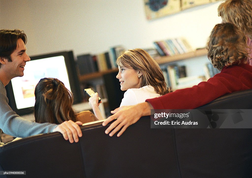 People sitting on couch, talking,  rear view, tv in background, tilt