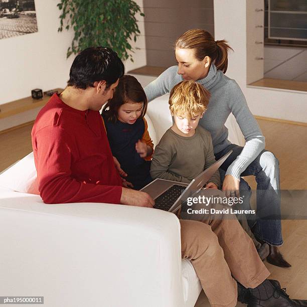 family sitting together on sofa, looking at laptop. - laurens foto e immagini stock