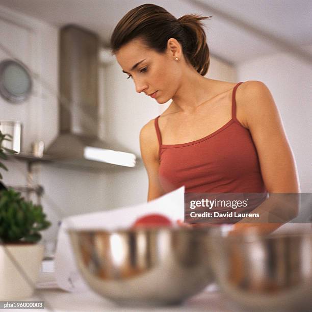 woman working in kitchen, waist up, bowls on counter in foreground, blurred - laurens foto e immagini stock