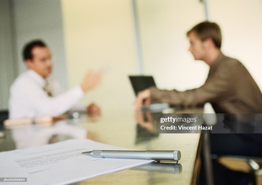 Businessmen working together in office space, blurred.