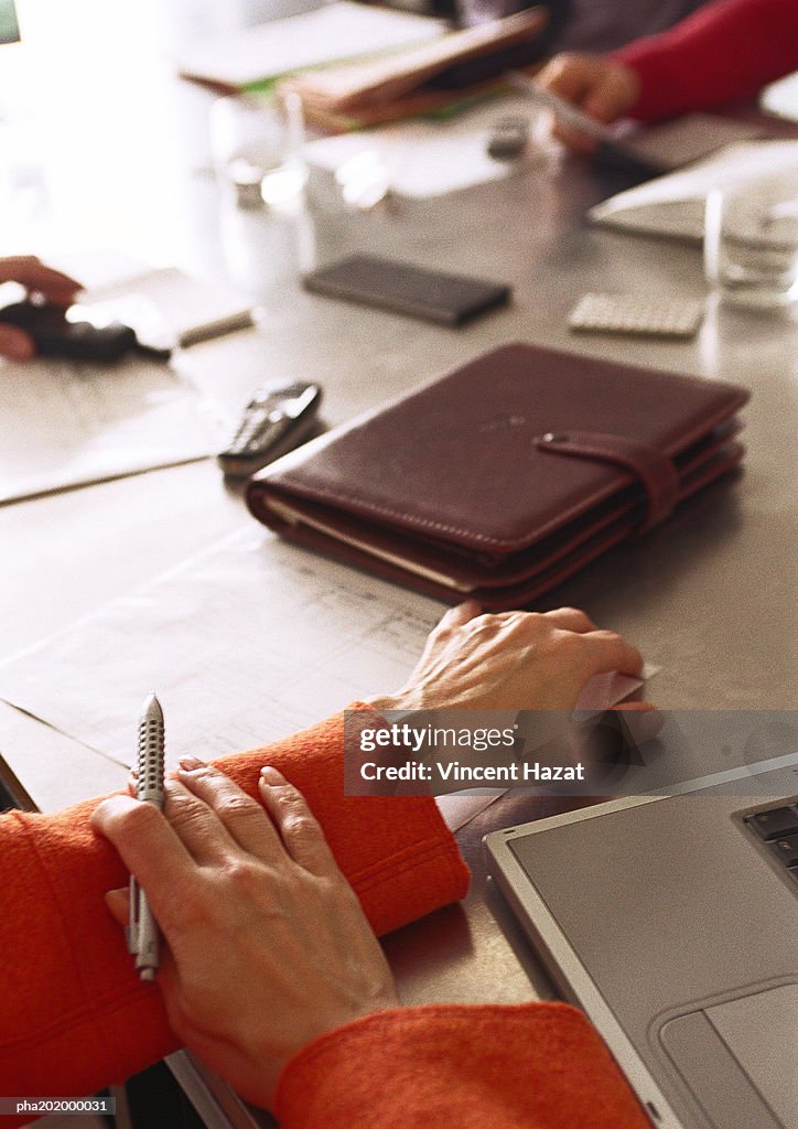 Businessman holding pen, view of table, close up.