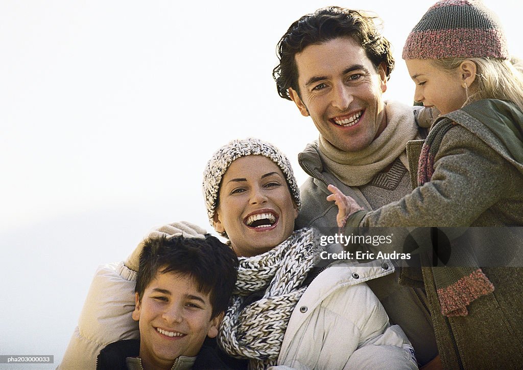 Adult man and woman with two children, smiling, warmly dressed,  oustside, portrait.