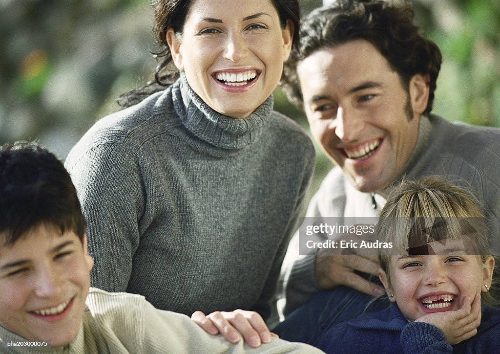 Adult man and woman with two children, head and shoulders, outside, close-up