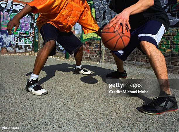 man dribbling basketball against opponent next to graffiti wall - africain stockfoto's en -beelden