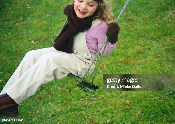 little girl smiling on a swing. - pflanzliche verfassung stock-fotos und bilder