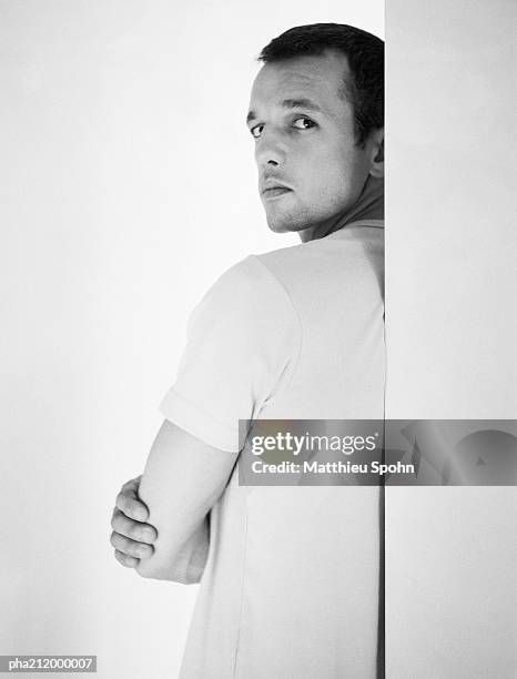 man standing behind a wall, looking into camera, rear view, b&w. - camera shy stock pictures, royalty-free photos & images