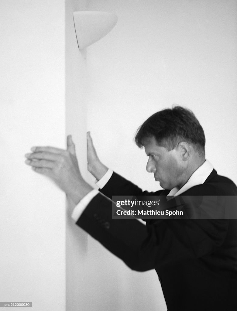 Man holding onto the wall, side view, b&w.