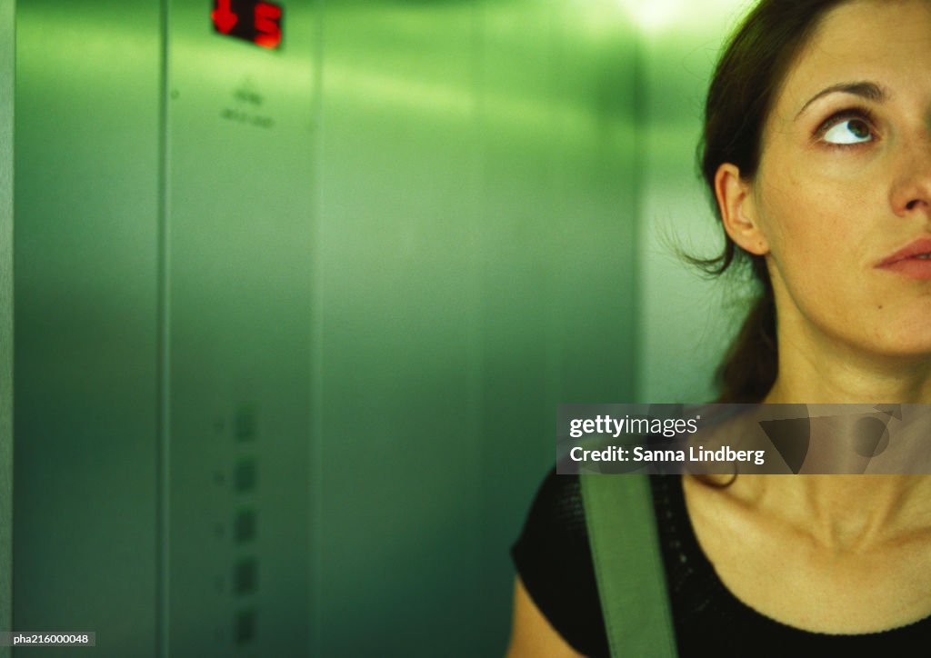 Woman in an elevator, head and shoulders, partial view, close-up.