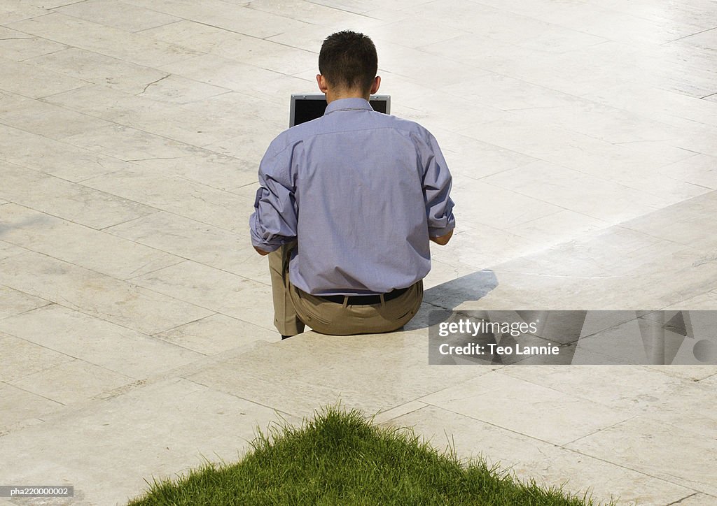 Man using laptop, rear view.