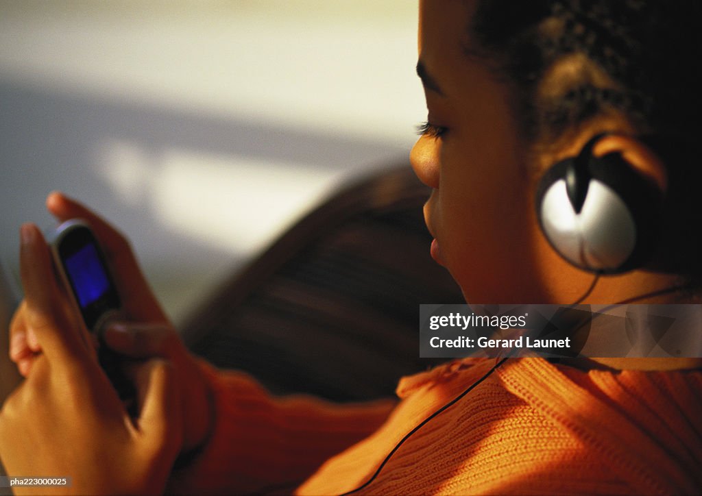 Young boy with headphones on looking at phone, close up.