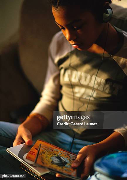 young boy with headphones on looking at books. - compacted stock pictures, royalty-free photos & images