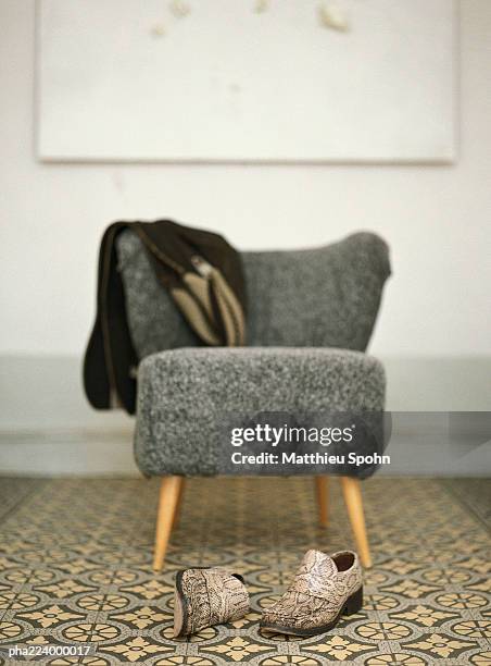 pair of shoes in front of chair with jacket draped over back. - back of chair stock pictures, royalty-free photos & images