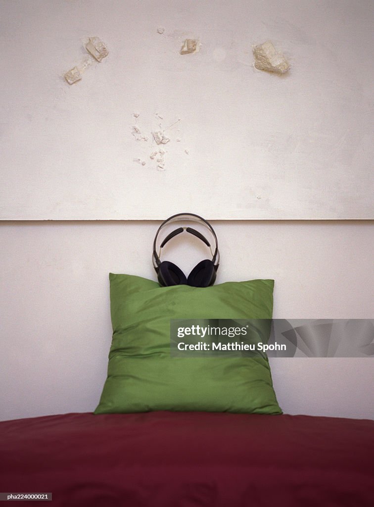 Headphones placed on top of pillow on couch.