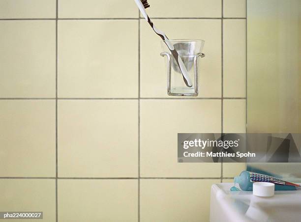 toothbrush in cup holder next to bathroom sink. - cup holder stock pictures, royalty-free photos & images