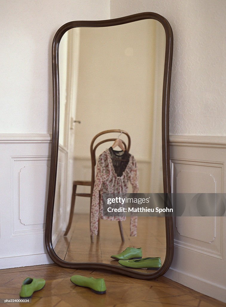 Mirror reflecting chair with blouse hanging from it.